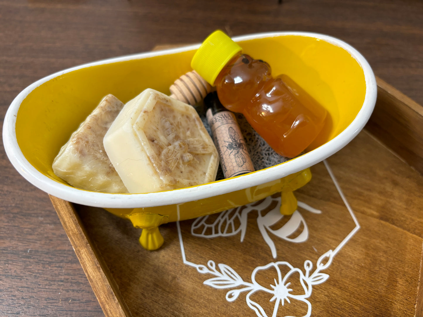 Honey, lip balm and small soap in a yellow bath tub.